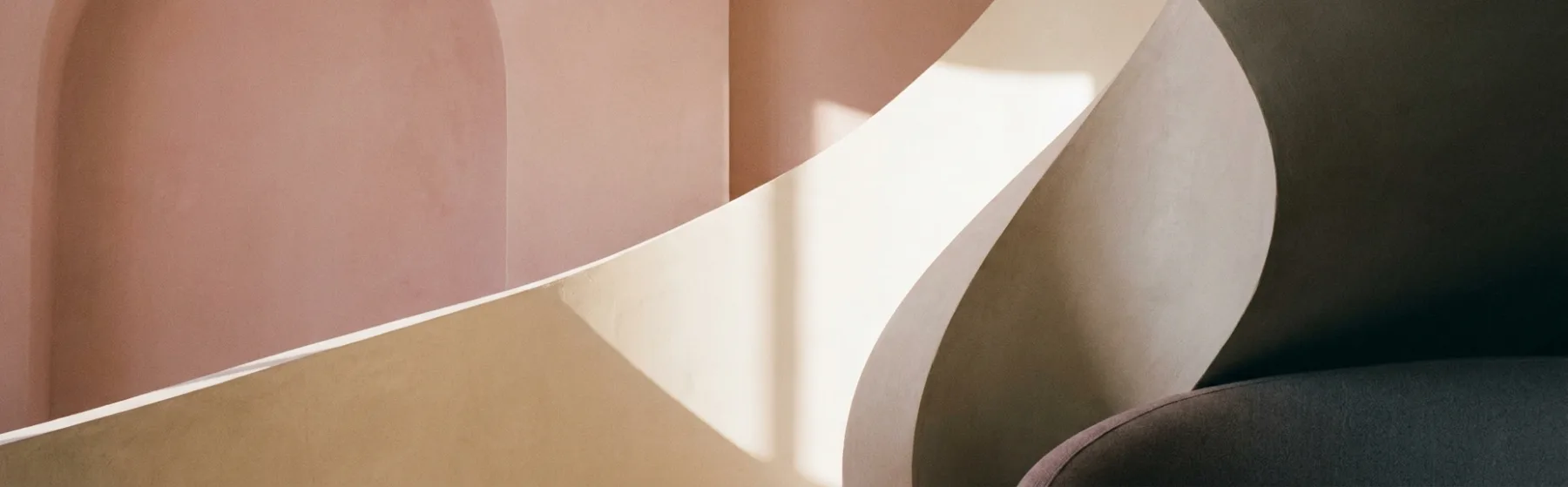 Overlapping curves of warm sand and blush plaster wall surfaces with a single soft shadow line
